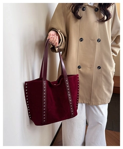 Detail of burgundy suede tote bag featuring silver studs and long leather handles
