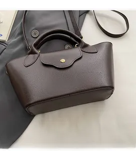 Detail of dark brown pebble leather handbag with gold metal stud and vintage trapezoid shape
