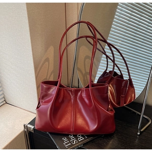 Detail of burgundy pleated leather tote bag showing textured folds and curved handle