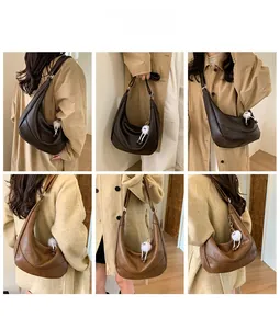 Detailed view of crescent shoulder bags in brown and caramel with plush charms