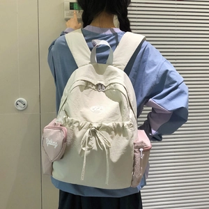 Detail eines cremeweißen Nylon-Rucksacks mit kleiner rosa Herztasche an der Seite