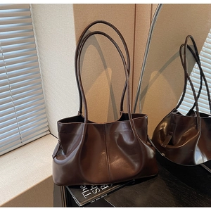 Detailed close-up of dark brown leather tote bag with soft pleated texture and slim straps