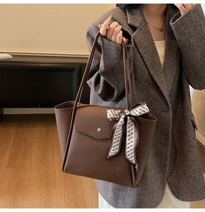 Detail of deep brown faux leather tote bag with elegant geometric patterned silk scarf handle
