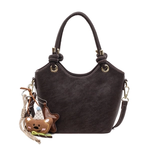 Minimalist dark brown bucket bag with plush charm and adjustable gold hardware strap