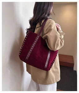 Close-up of wine red suede tote bag featuring silver studs and premium metal details