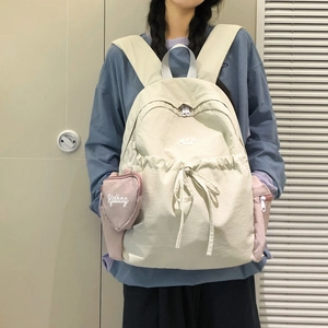 Detailansicht cremeweißer Canvas-Rucksack mit rosa Herzanhänger und Kordelzugverschluss