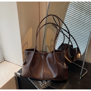 Detailed close-up of dark brown pleated tote bag with matte leather texture and slim straps