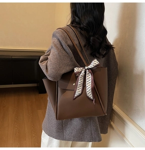 Detail of deep brown leather tote bag with lychee texture and decorative silk scarf