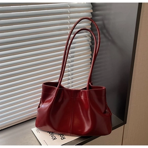 Detailed macro view of the deep red pleated leather texture on a stylish tote bag