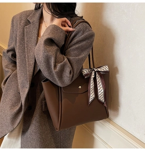 Detail view of coffee brown lychee leather tote bag with silk scarf and gold buckle pocket