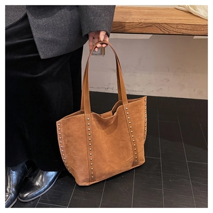 Detail shot of brown suede tote bag featuring silver studs and long shoulder straps