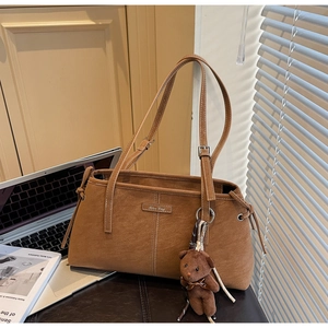 Detail view of brown vintage tote bag with drawstring side and cute teddy bear charm