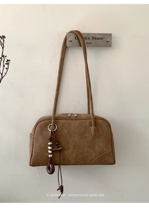 Detail of vintage brown suede shoulder bag with dual zippers and bead pendant