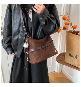 Detail of dark brown matte shoulder bag with star applique, ribbon bow and plush pompom