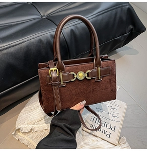 Detail of vintage suede shoulder bag featuring a golden heart-shaped lock and handle