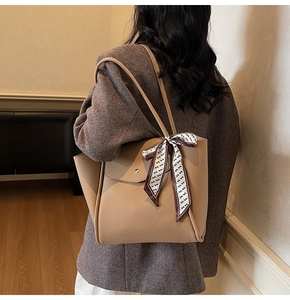 Detail of khaki leather tote bag with lychee pattern and decorative printed scarf
