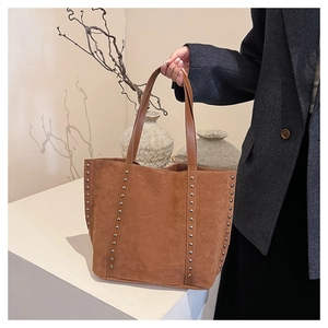 Detail of silver rivets on brown suede tote bag featuring high-quality vintage texture