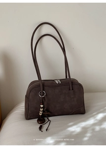 Close-up of a retro brown suede shoulder bag with a unique beaded charm detail