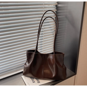 Detail of dark brown tote bag with pleated leather texture and slim shoulder straps