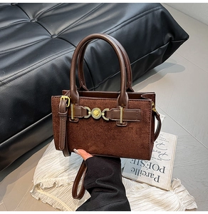 Detail of dark brown handbag with gold heart buckle and suede leather stitching textures