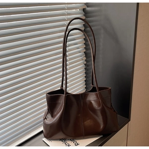 Close-up of deep brown tote bag with pleated texture on a windowsill under natural light