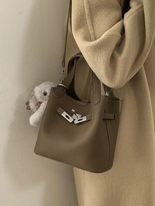 Brown lychee leather bucket bag with metal buckle and plush bunny charm on coat