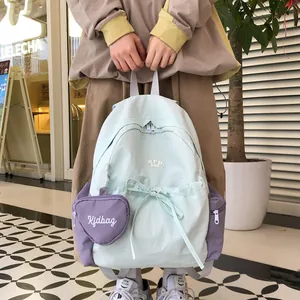Detail eines mintgrünen Nylon-Rucksacks mit lila Herztasche und Kordelzugverschluss