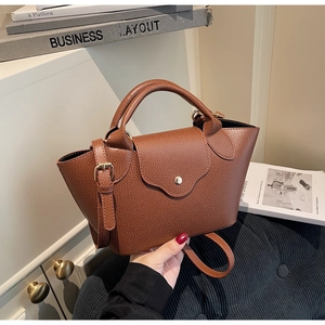 Detailed view of brown lychee grain leather bucket bag with metallic twist lock
