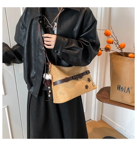 Detail of light brown suede shoulder bag with star patches and tassel charms on a jacket