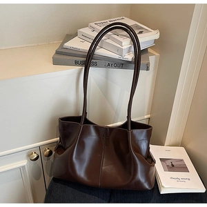 Close-up of a large dark brown pleated tote bag in a minimalist lifestyle setting