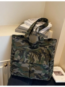 Camo canvas tote bag with dual front pockets and wide shoulder strap in workwear style