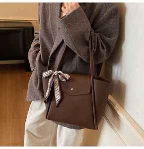 Detail of dark brown leather tote bag with elegant floral scarf and gold clasp closure