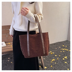 Deep brown suede tote bag with silver studs styled for a professional autumn commute