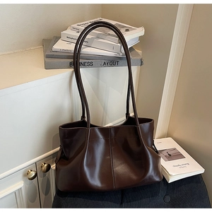 Detailed view of dark brown pleated tote bag with fine stitching and long slim handles