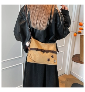Detailed back view of a brown suede crossbody bag with star patches and pompom charm