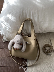 Chic beige pebbled leather bucket bag with silver twist lock and plush bunny charm
