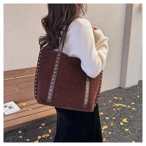 Detailed view of dark brown suede tote bag featuring silver studs and long shoulder straps