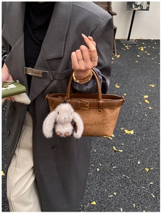 Detail of brown suede mini tote bag with belt buckle and grey plush bunny charm