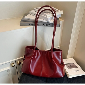 Detail of burgundy leather tote showing pleats, vertical stitching, and soft texture