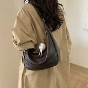 Detail of dark brown leather hobo bag with a cute white plush monster keychain pendant