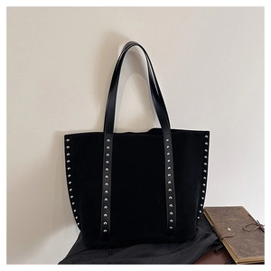 Detail shot of silver rivets and matte suede texture on a black commute tote bag