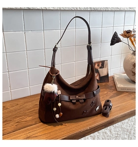 Macro shot of dark brown suede tote bag with star charm and decorative plush pendant