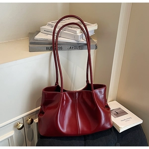 Detail of burgundy tote bag featuring unique pleated design on a clean white background