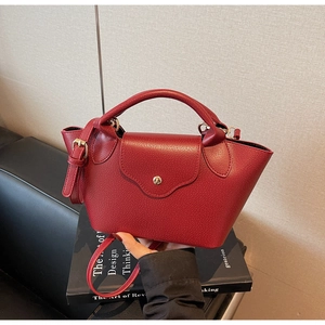 Detail of burgundy lychee grain bucket bag with gold clasp and adjustable strap