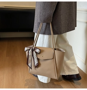 Detail of beige French tote bag featuring a leather texture and elegant silk scarf accessory