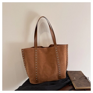 Detail view of the suede tote bag showing silver rivets and high-quality leather texture