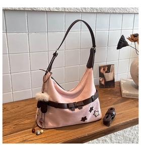 Pink suede hobo bag detail with star patches, bow, and plush glove charm accessory