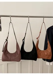 Detail view of suede hobo bags in coffee, black and caramel colors hanging on hooks