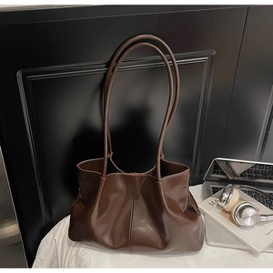 Detail of dark brown pleated tote bag styled with laptop and headphones for office commute