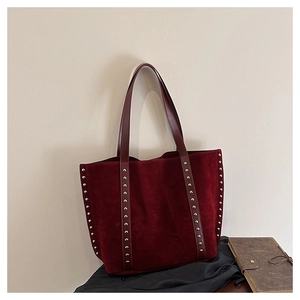 Macro detail of wine red suede tote bag with silver rivets and leather handle
